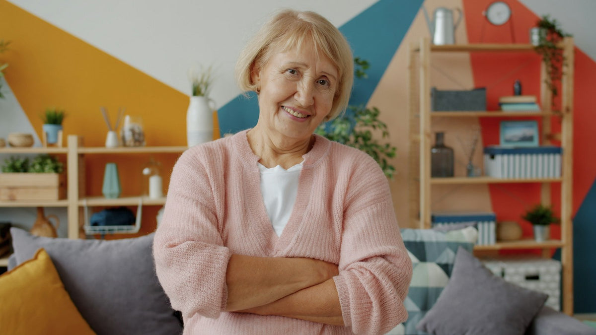 Lächelnde Frau ab 50 in rosa Strickjacke im Wohnzimmer